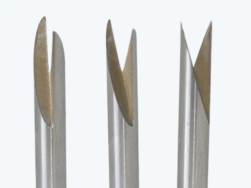 Drei Bohrer mit scharfen Schneiden und goldfarbenen Spitzen liegen nebeneinander vor hellem Hintergrund und zeigen ihre unterschiedlichen Formen.