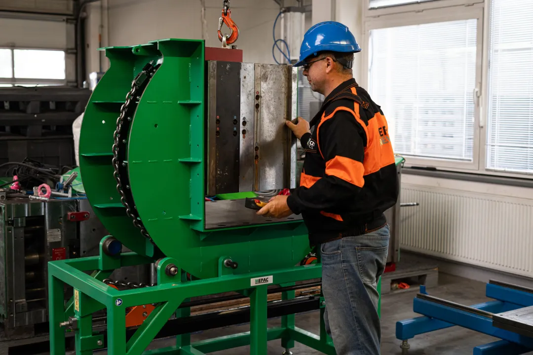 Ein Arbeiter mit blauem Schutzhelm bedient den grünen Mechanischen Formenwender KCA in einer Werkhalle.