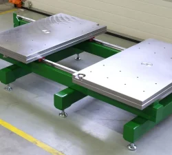 Grüner Werkzeugöffner KFM mit zwei breiten silbernen Ladeblättern steht in einer Werkhalle auf Rollen und zeigt die robuste, kompakte Konstruktion.