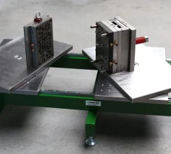 Ein grünes mobiles Werkzeugöffner-System hält zwei Spritzgussformen auf schrägen Platten, während die Trennebene klar geöffnet bleibt.