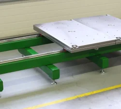 Ein grüner Werkzeugöffner mit metallischer Auflageplatte steht im geschlossenen, unbeladenen Zustand auf dem Hallenboden.