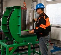 Ein Arbeiter mit blauem Schutzhelm bedient den grünen Mechanischen Formenwender KCA in einer Werkhalle.
