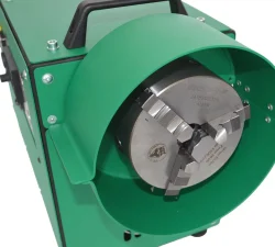 Ein grünes Spannfutter mit massiven Metallbacken sitzt in einer Poliermaschine und trägt eine technische Beschriftung.