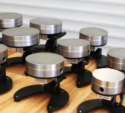 Mehrere magnetische Werkstückhalter mit runden Metallplatten stehen auf einem Holztisch vor einer hellen Wand.