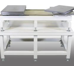 Zu sehen ist eine verstellbare Werkzeug- und Formenöffner-Anlage mit weißem Untergestell, Inspektionstisch und zwei grauen Auflageplatten.