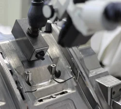 Schaltbarer Magnetfuß des Werkstattmikroskops auf einer Spritzgussform, Stereomikroskop mit Gelenkarm darüber